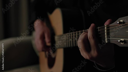 To play guitar A man plays the guitar in a dark room. Close-up of a guitar neck