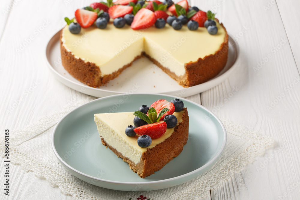 Homemade New York cheesecake slice decorated with fresh berries closeup on the plate on the wooden table. Horizontal Homemade New York cheesecake slice decorated with fresh berries closeup on the plate on the wooden table. Horizontal