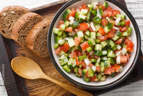 Tasty Pipirrana is a simple Spanish salad from Andalusia with tomatoes, cucumbers, bell peppers and onion closeup on the plate on the table. Horizontal top view from above