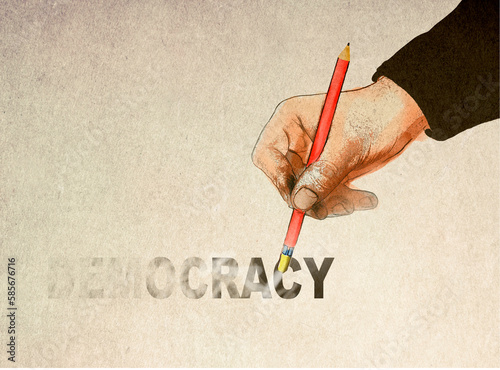 Hand holding pencil and erasing democracy text photo
