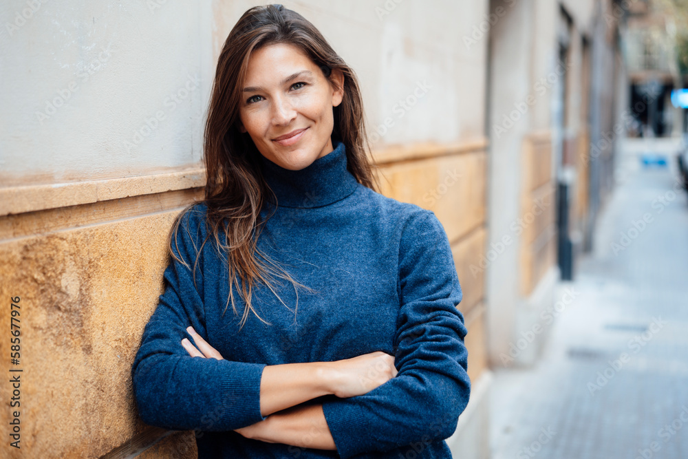 Smiling woman with arms crossed leaning on wall Smiling woman with arms crossed leaning on wall