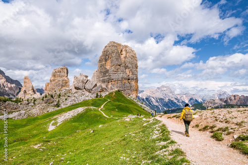 Young female is admiring Cinque Torri in Dolomites mountains in Italy photo