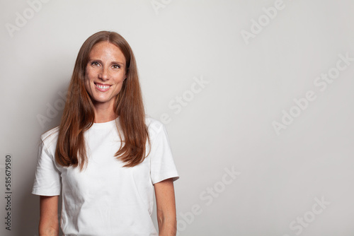 Healthy woman in white t-shirt smiling, closeup studio portrait