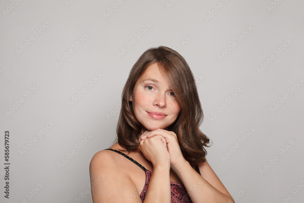 Close up studio shot of beautiful young brunette woman model with curly hair looking at camera with charming cute smile while posing against white studio wall background Close up studio shot of beautiful young brunette woman model with curly hair looking at camera with charming cute smile while posing against white studio wall background