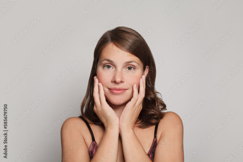 Pretty woman with natural fresh healthy skin touching her cheeks her hands on white Pretty woman with natural fresh healthy skin touching her cheeks her hands on white