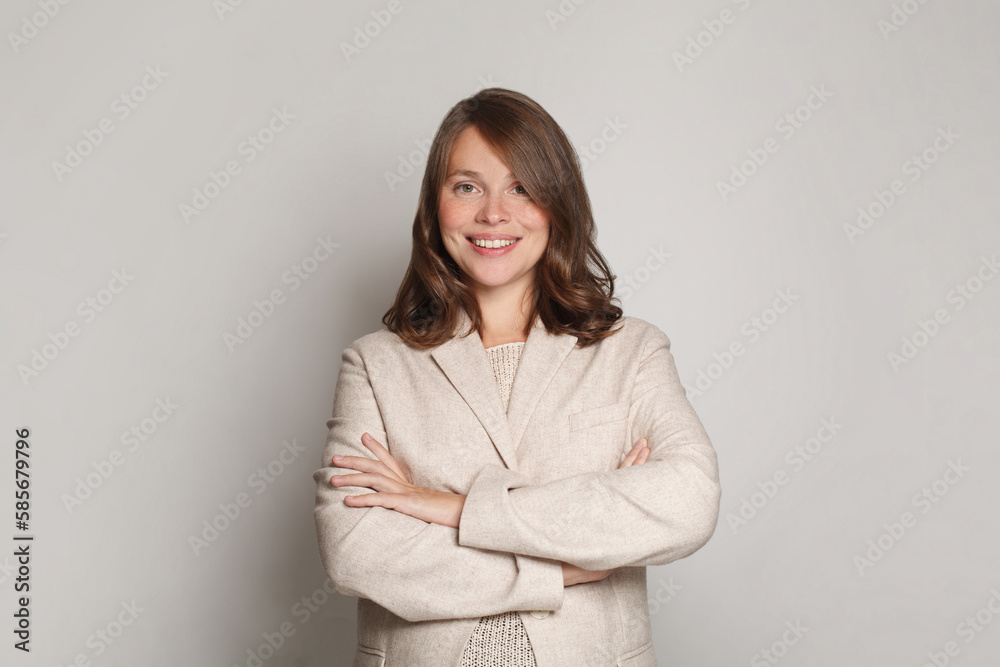 Friendly business woman portrait. Female model standing with crossed arms against grey studio wall banner background Friendly business woman portrait. Female model standing with crossed arms against grey studio wall banner background