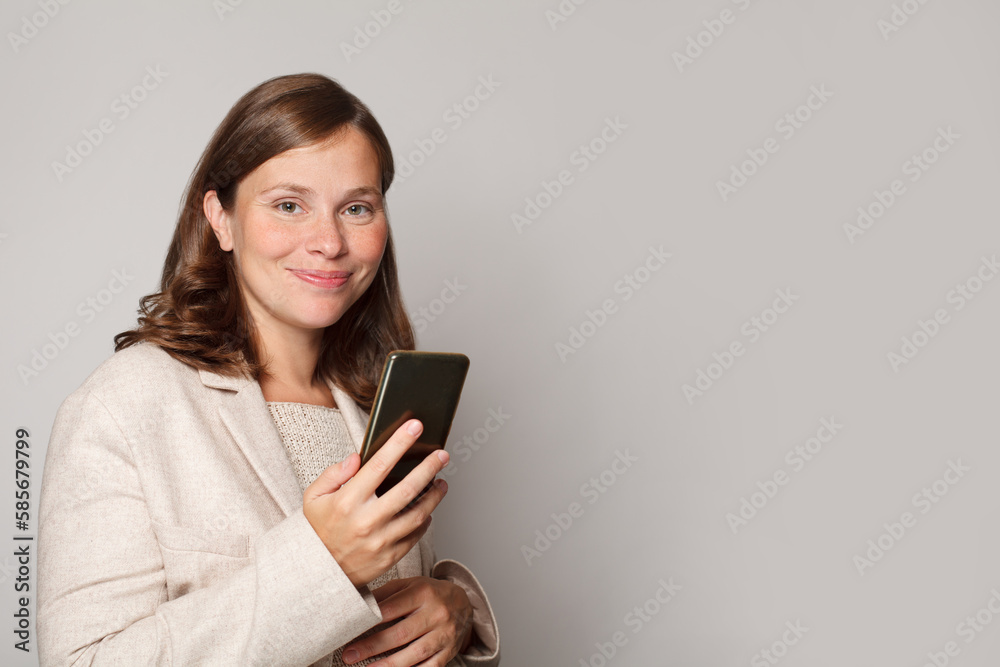 Young pregnant woman using her mobile phone to send message against white studio wall background Young pregnant woman using her mobile phone to send message against white studio wall background