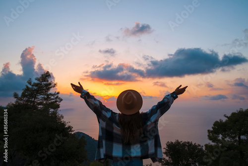 Woman with arms outstretched enjoying sunset on vacation photo