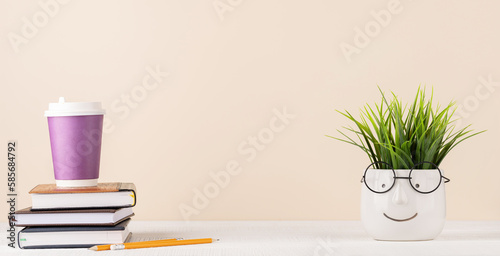 Coffee cup on stack of notepads and plant