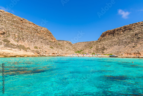 Cala Pulcino in Lampedusa seen from a boat. Stunning turquoise sea water in a secluded bay surrounded by cliffs. Sicily  Italy.
