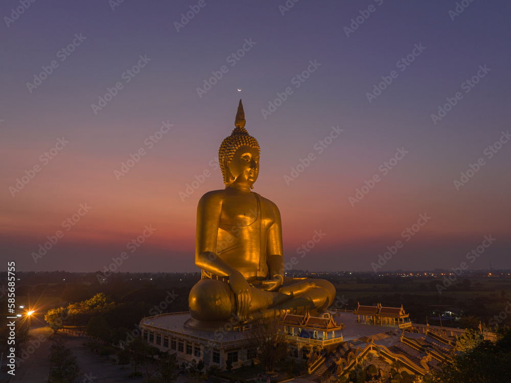 Obraz premium aerial view The moon on the head of golden big Buddha. the Biggest Buddha in the world at wat Maung Angtong Thailand. scenery sky in twilight background.the one famous landmarks in Thailand. 