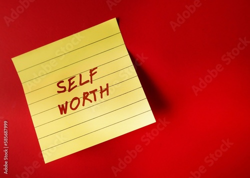 Yellow paper note on red background with handwritten text SELF WORTH, refers to self-love, being confidence with self-esteem - giving yourself respect, dignity and understanding