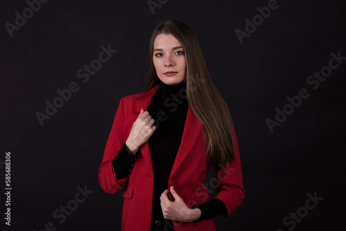 Portrait of a businesswoman in a red suit on a black background.