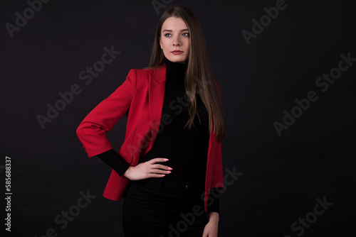 Portrait of a businesswoman in a red suit on a black background. © Павел Костенко