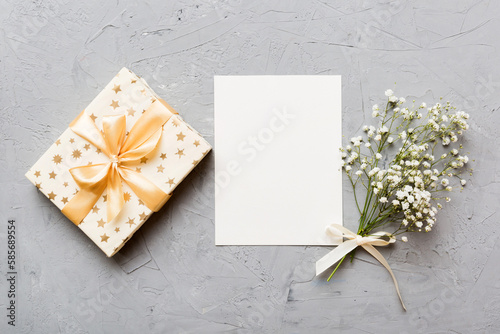 Wedding mockup with white paper list and flowers gypsophila on colored table top view flat lay. Blank greeting cards and envelopes. Beautiful floral pattern. Flat lay style © sosiukin