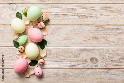 Happy Easter. Easter eggs on colored table with yellow roses. Natural dyed colorful eggs background top view with copy space