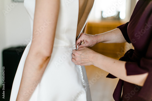 Braut beim Anziehen des Brautkleids