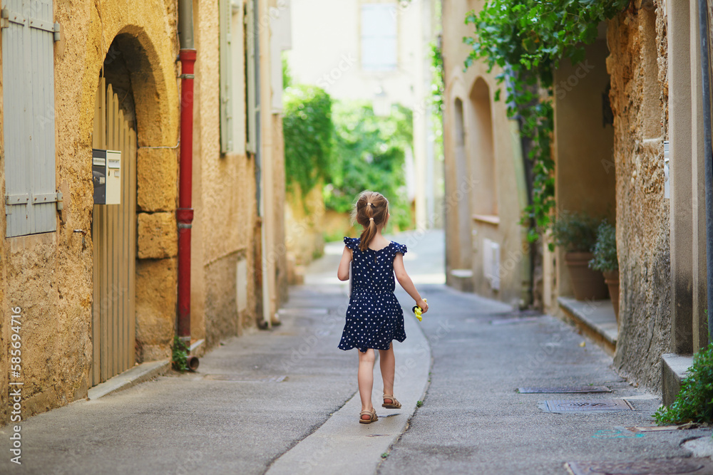 Adorable preschooler girl walking on a street of Medieval village of Lourmarin in Southern France