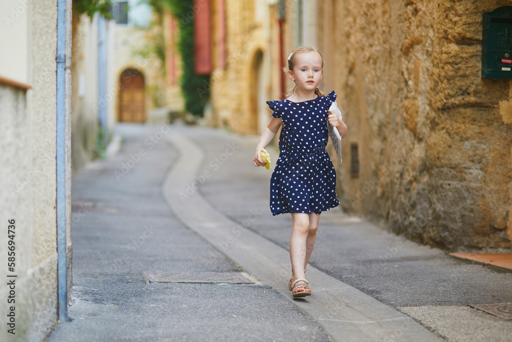 Adorable preschooler girl walking on a street of Medieval village of Lourmarin in Southern France Adorable preschooler girl walking on a street of Medieval village of Lourmarin in Southern France