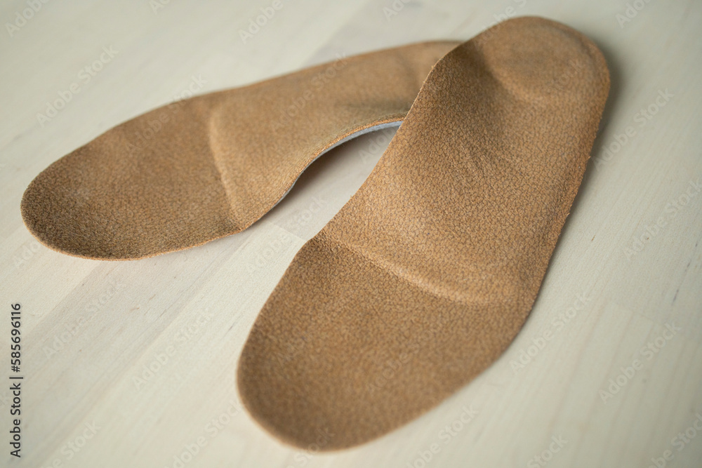 Fototapeta premium orthopedic insoles for shoes brown, made of natural materials, lies on a light surface of the table. Prevention and treatment of flat feet, shoe accessories