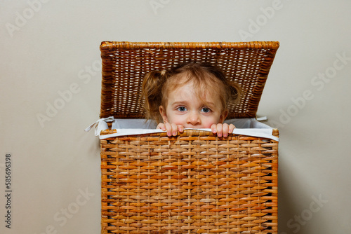 Close portrait of a girl play hide-and-seek in laundry box