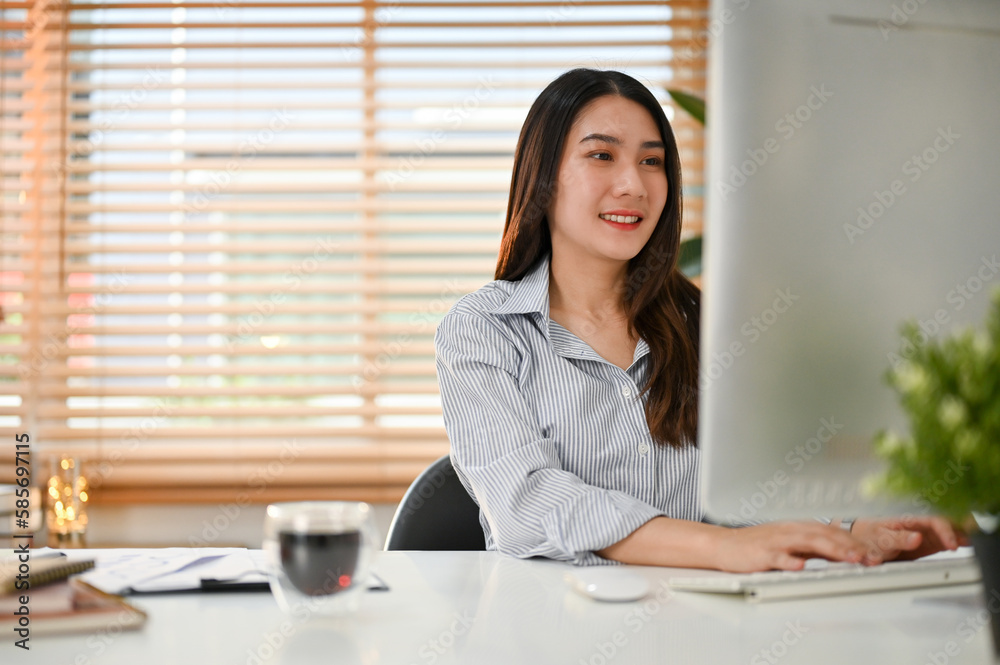 Charming Asian businesswoman working on her project on computer at her desk Charming Asian businesswoman working on her project on computer at her desk