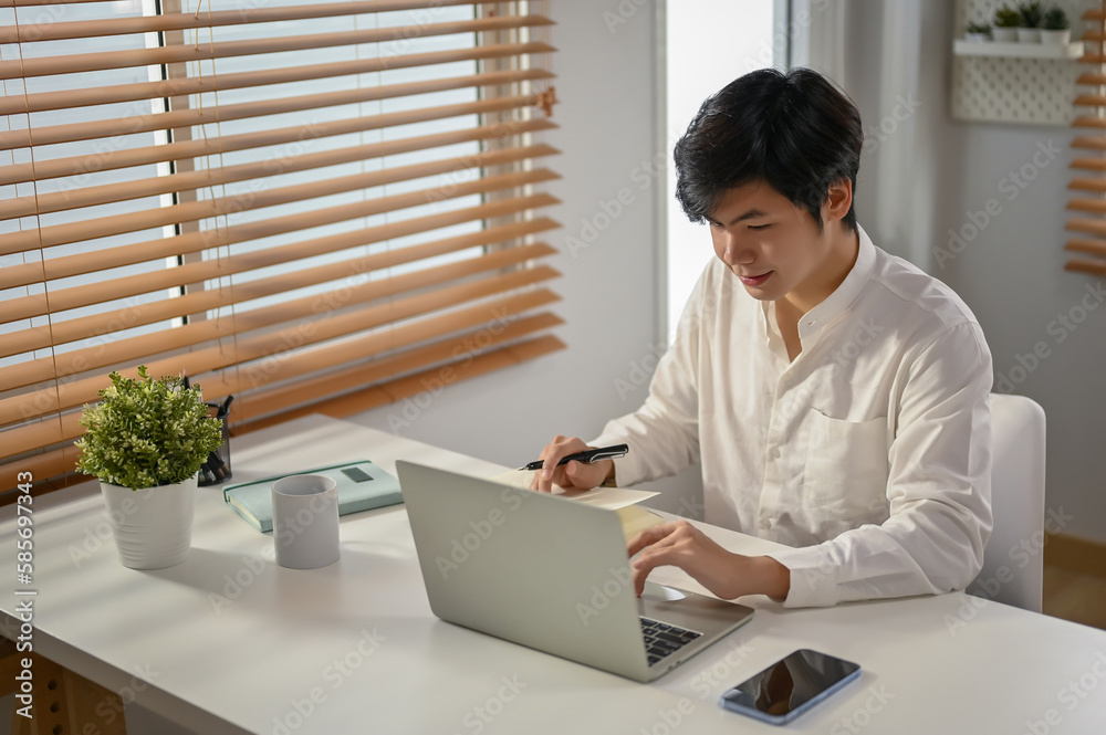 Smart Asian businessman working on his business tasks on laptop at his workspace