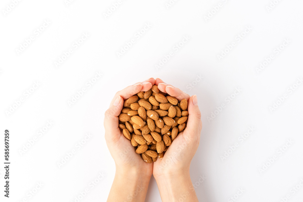 Overhead shot of woman’s hands holding almonds isolated on white background
