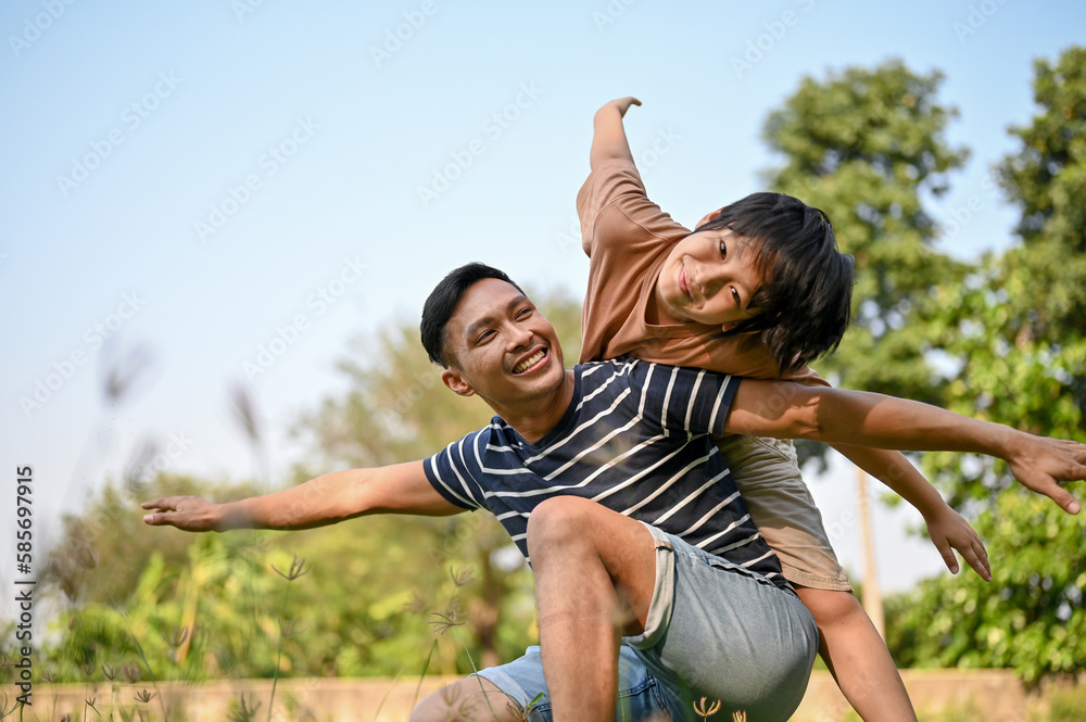 Excited and cheerful young Asian boy piggybacking on his father. Excited and cheerful young Asian boy piggybacking on his father.