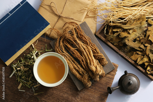 Angelica sinensis roots on a rectangular tray, medicine cup, blue book, medicine package and some dries herb on light background. Scene for advertising, photography traditional medicine content photo