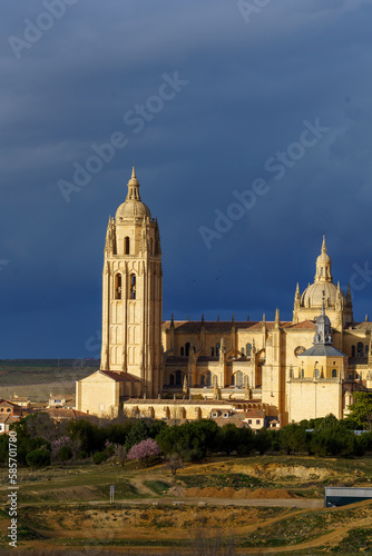 Tower of the cathedral church of Segovia with blue sky and clouds in the background and birds in flight
