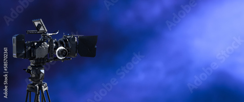 Digital movie camera filming in the dark with smoke and blue lightning background. television, broadcast, video, film studio or movie production background with copy space