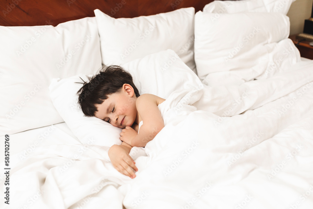 Cute little boy sleeping. Tired child taking a nap in parent's bed. Clean, fresh and cozy bedding sheets. Bedtime for kids. Cute little boy sleeping. Tired child taking a nap in parent's bed. Clean, fresh and cozy bedding sheets. Bedtime for kids.