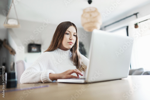 young girl at home in front of the laptop doing her homework, distance learning