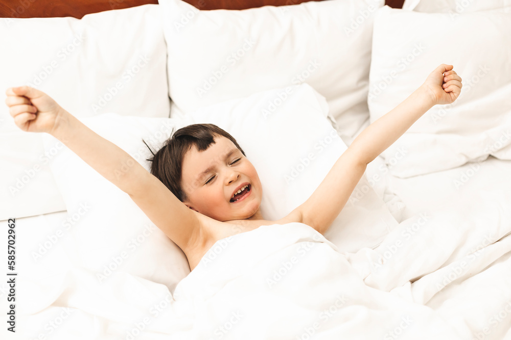 Little boy lying and stretching his arms in the bed at home in the morning. Home lifestyle boy relaxing sleeping on bed in bedroom. Little boy lying and stretching his arms in the bed at home in the morning. Home lifestyle boy relaxing sleeping on bed in bedroom.