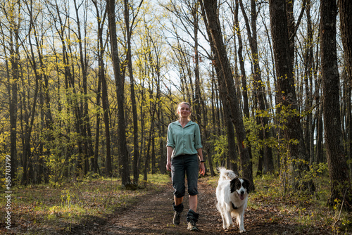 woman trekking in forest with dog