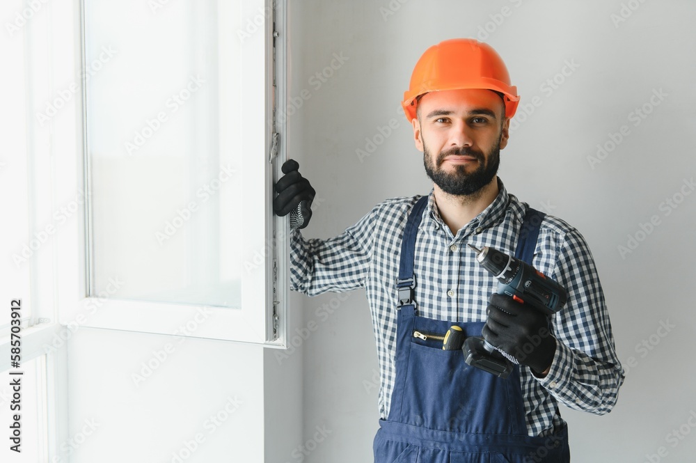 Worker in installing white plastic upvc window on house.