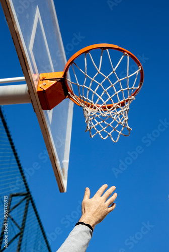 basketball hoop against blue sky and hand trying to get touched it  sport and winning concept  vertical