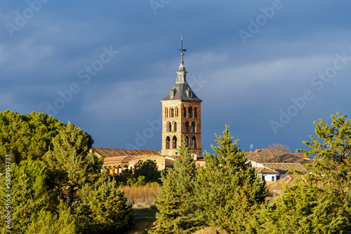 Church tower of the Monasterio el Parral de Segovia between trees with a stormy blue skyChurch tower of the monastery El Parral in Segovia between trees with a stormy blue sky