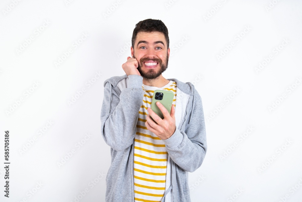 Joyous Young caucasian mán wearing trendy clothes over poses with mobile phone device, types text message on modern smartphone, watches funny video during free time, enjoys good internet connection, Joyous Young caucasian mán wearing trendy clothes over poses with mobile phone device, types text message on modern smartphone, watches funny video during free time, enjoys good internet connection,