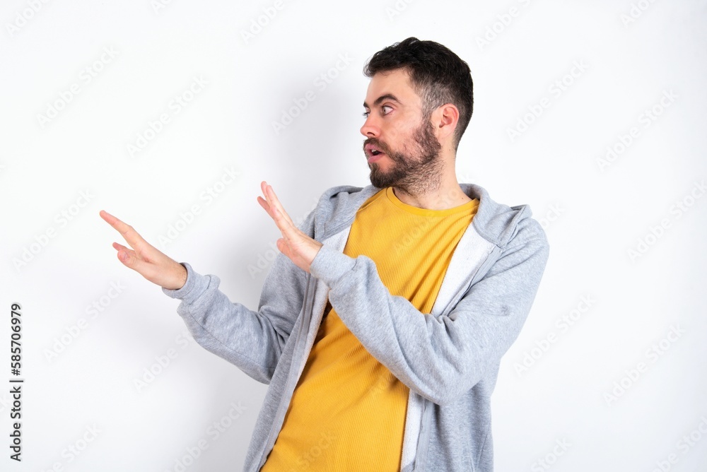 Displeased Young caucasian mán wearing trendy clothes over white background keeps hands towards empty space and asks not come closer sees something unpleasant Displeased Young caucasian mán wearing trendy clothes over white background keeps hands towards empty space and asks not come closer sees something unpleasant