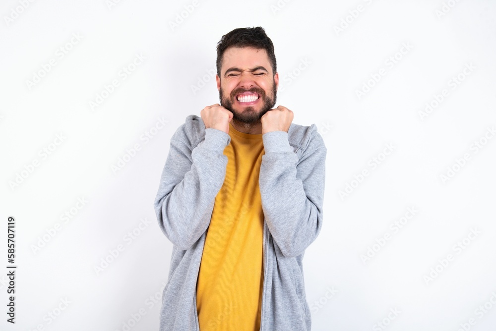 Young caucasian mán wearing trendy clothes over white background grins joyfully, imagines something pleasant, copy space. Pleasant emotions concept. Young caucasian mán wearing trendy clothes over white background grins joyfully, imagines something pleasant, copy space. Pleasant emotions concept.