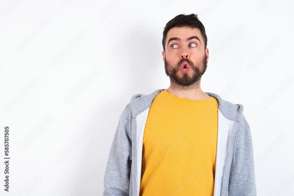 Shocked Young caucasian mán wearing trendy clothes over white background look empty space with open mouth screaming: Oh My God! I can't believe this. Shocked Young caucasian mán wearing trendy clothes over white background look empty space with open mouth screaming: Oh My God! I can't believe this.