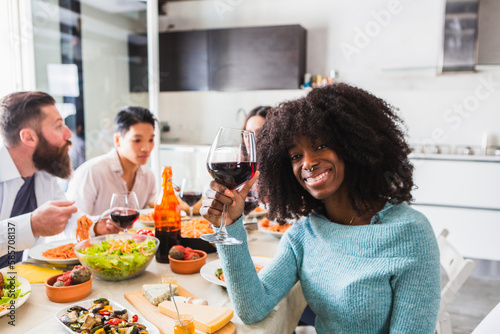 African girl with afro hair proposing a toast during a lunch