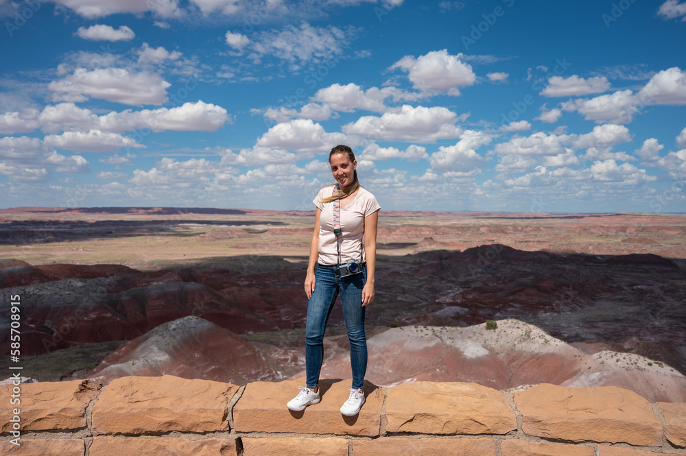 Naklejka premium Smiling blonde young girl with a photo camera in the Petrified Forest National Park
