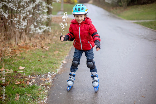 Little child, preschool boy in protective equipment and rollers blades, riding on walkway