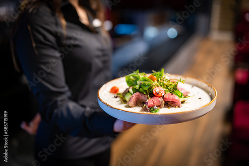 Fototapeta Naklejka Na Ścianę i Meble -  Waiter holds a plate with salad in the restaurant.