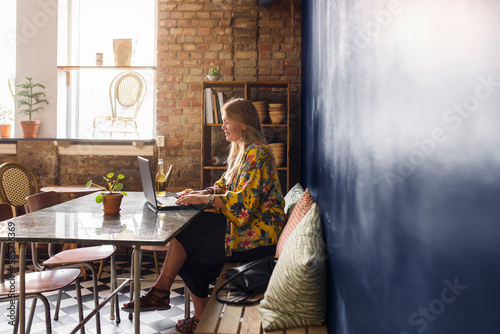 Woman using laptop in bakery
