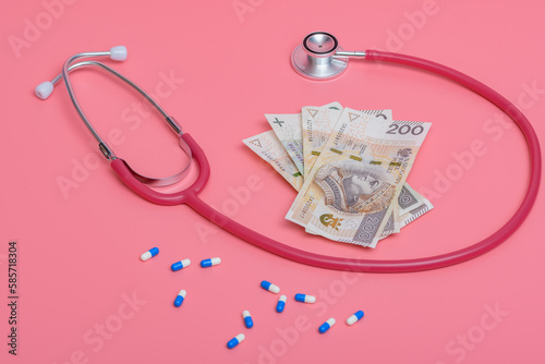 Drogie koszty leczenia - gotówka z lekarstwami i stetoskopem na różowym tle