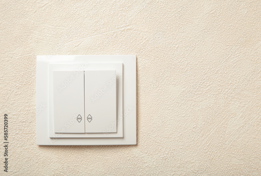 Light switch, a plastic mechanical switch of white color installed on a light wall. Light switch, a plastic mechanical switch of white color installed on a light wall.